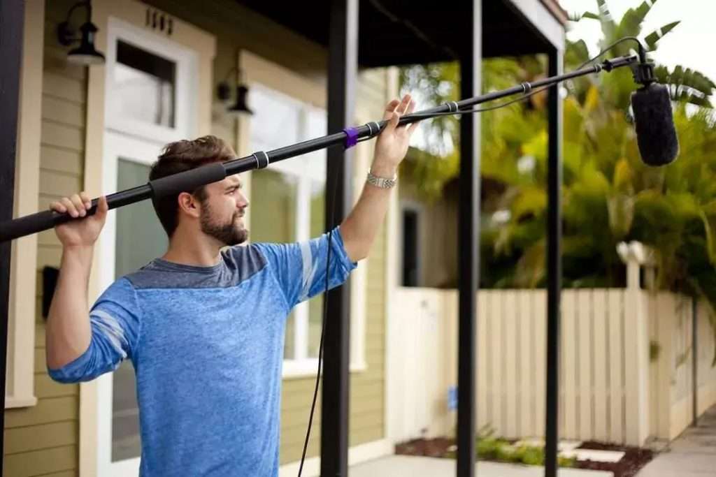 audio for video production. man holding a boom and shotgun mic.